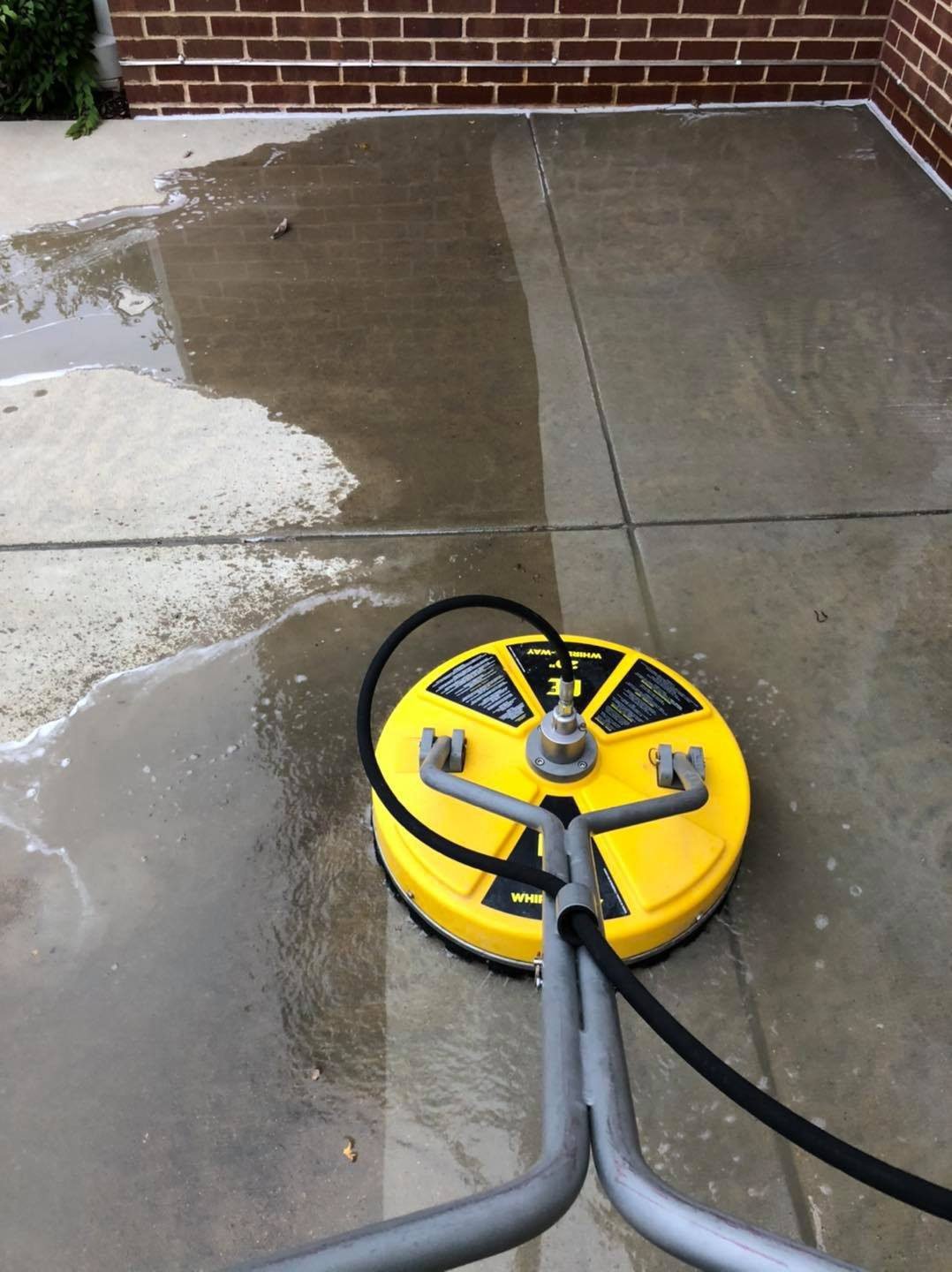 Before and after results of a driveway cleaned with pressure washing in Arlington WA using a surface cleaner
