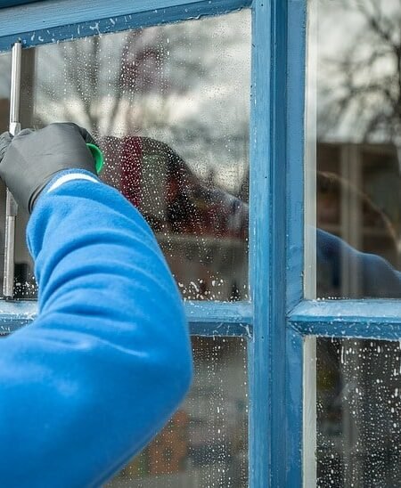 Technician performing commercial window cleaning in Marysville WA using a squeegee on a storefront window