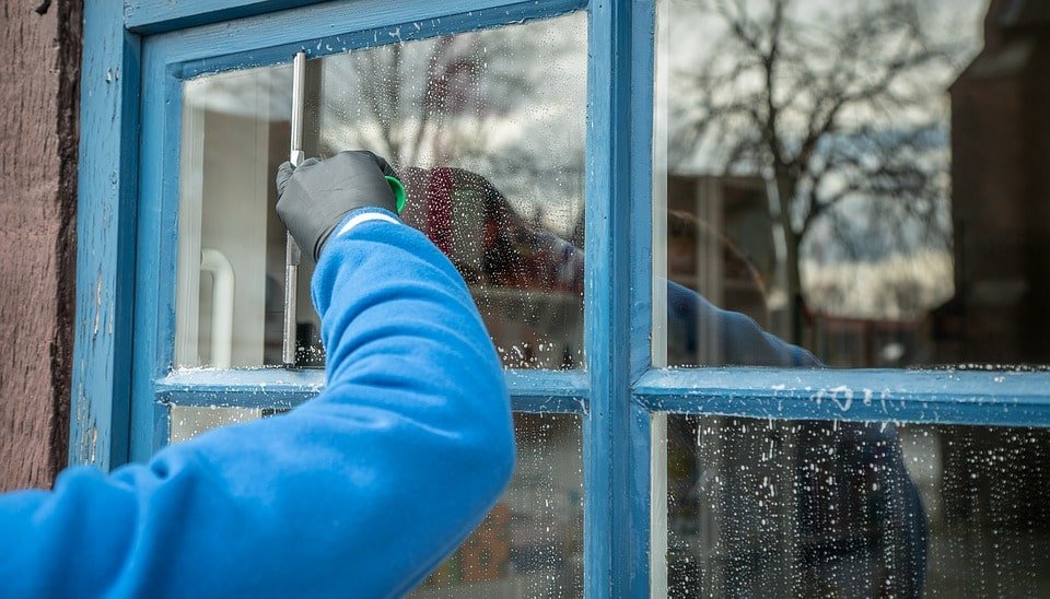 Technician performing commercial window cleaning in Stanwood WA using a squeegee on a storefront window