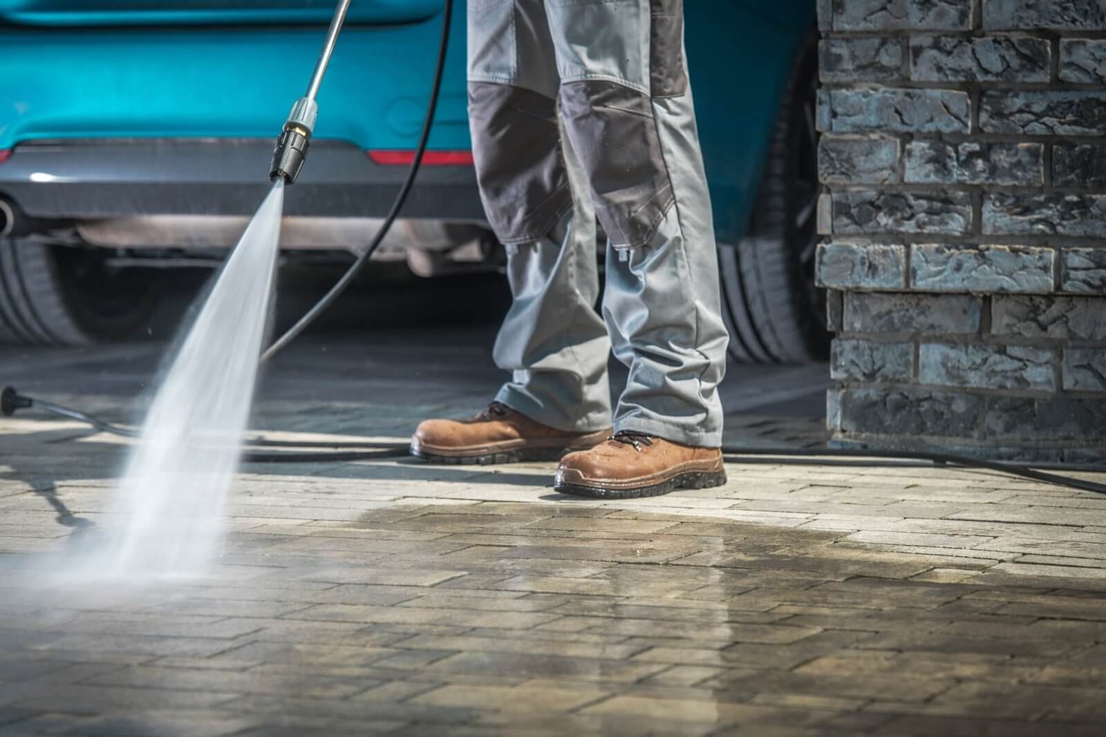 Technician performing pressure washing in Arlington WA on a residential driveway
