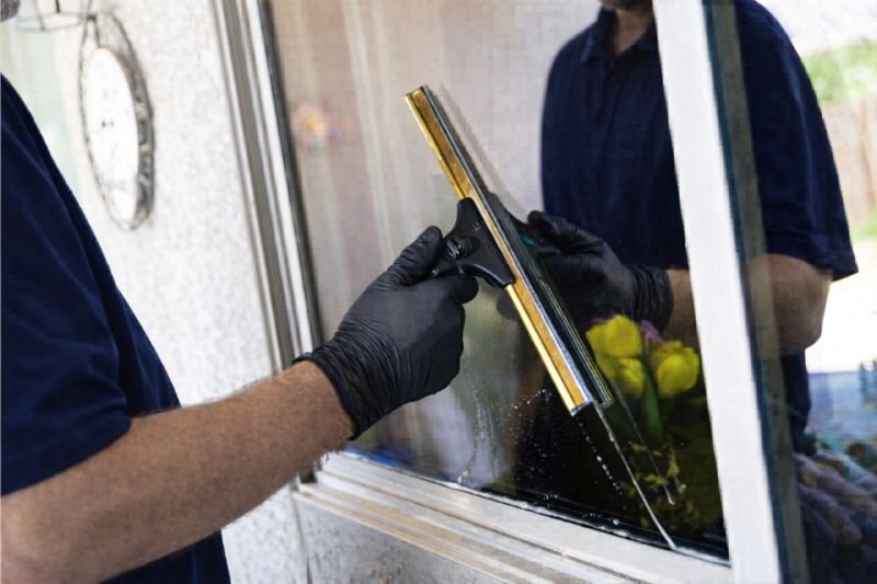 Technician performing window cleaning near Marysville WA with a squeegee on a wet window